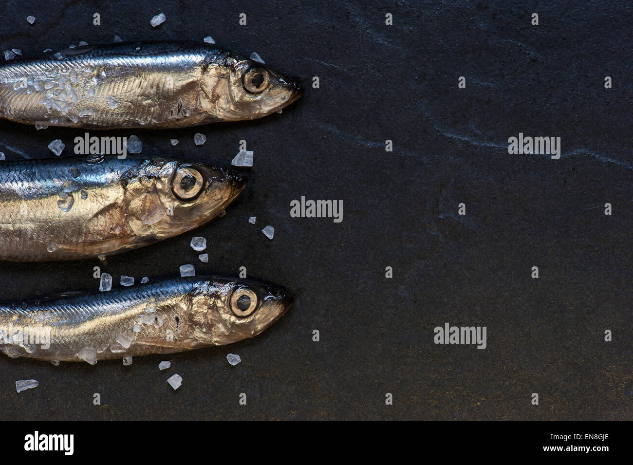 Piccoli pesci con sale sul tavolo Foto Stock