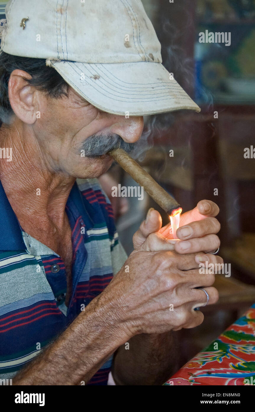 Ritratto verticale di un uomo cubano illuminazione di un sigaro. Foto Stock