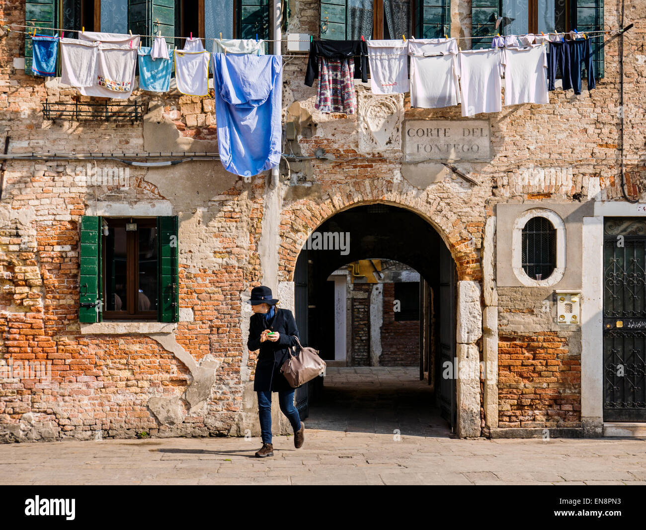 Donna cammina al di sotto della biancheria appesa ad asciugare, Venezia, Italia, città dei canali Foto Stock