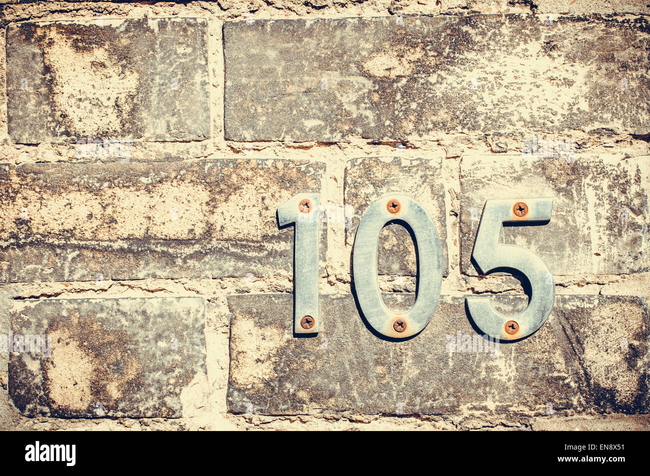 Weathered numero di casa e un centinaio di cinque su un muro di mattoni Foto Stock