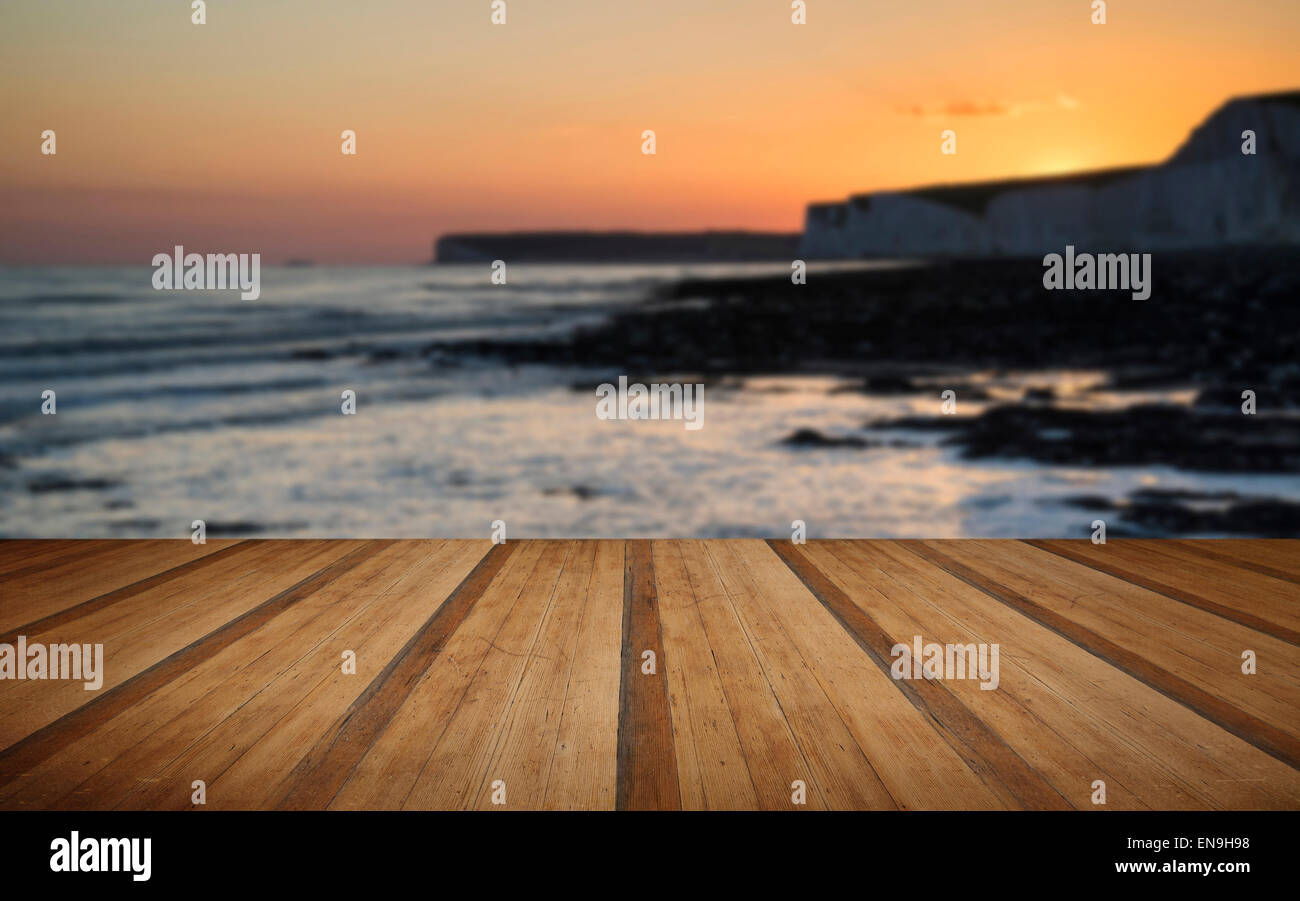 Immagine di panorama della spiaggia rocciosa al tramonto con una lunga esposizione motion blur mare con doghe in legno piano Foto Stock