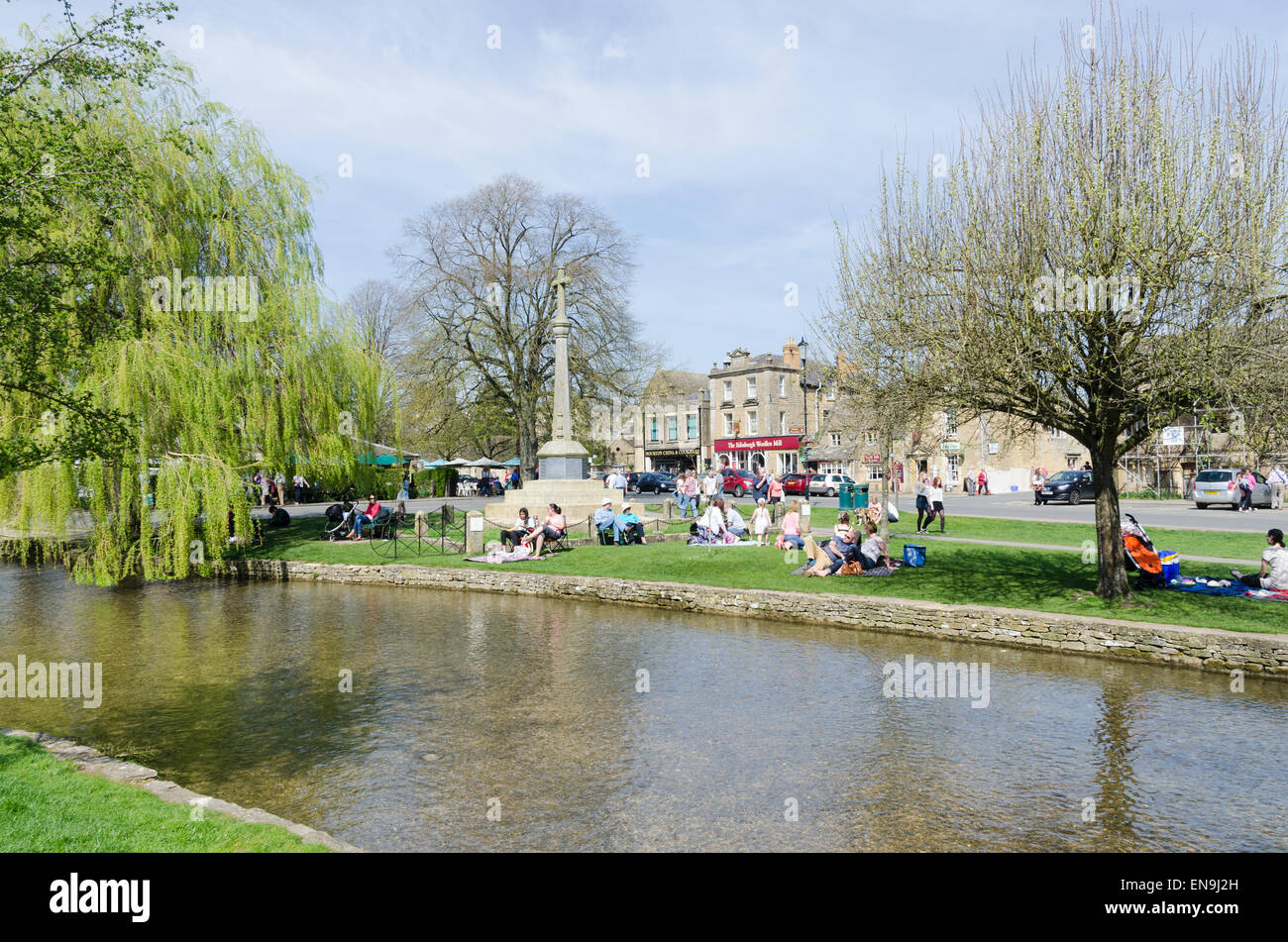 Gli ospiti godono di pic-nic a lato del Fiume Windrush in esecuzione attraverso Bourton sull'acqua in Cotswolds Foto Stock