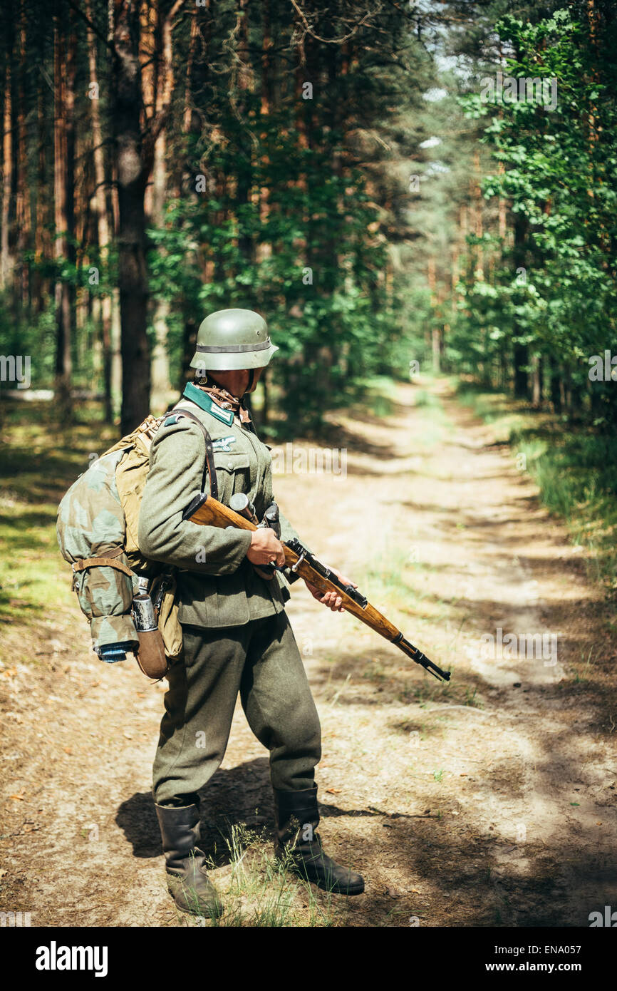 Unidentified ri-enactor vestito come soldato tedesco durante il mese di marzo attraverso la foresta di estate. Rievocazione storica Foto Stock