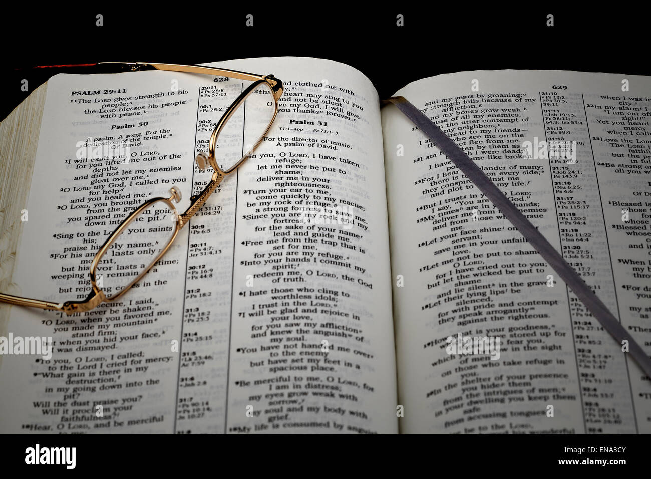 Lo studio della Bibbia il Salmo 30 nella luce della sera con gli occhiali da lettura su sfondo nero Foto Stock