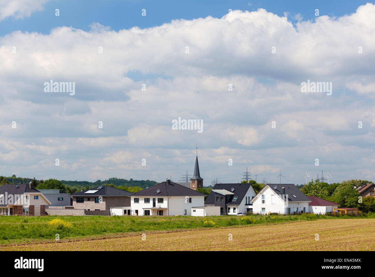 Area di sviluppo di un villaggio con lucido nuove case e una chiesa in background Foto Stock