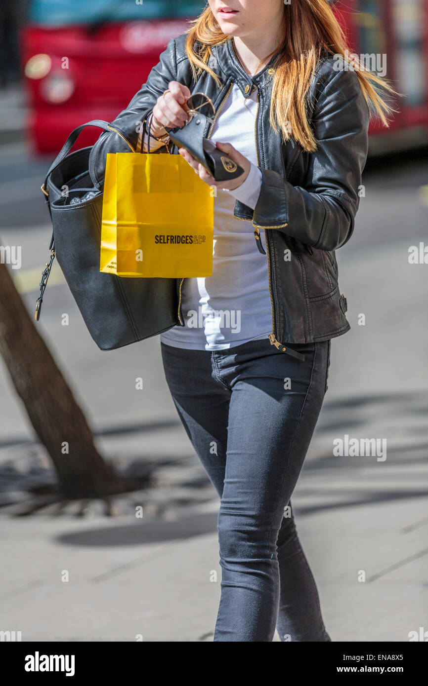 Una giovane donna cammina con Selfridges & Co shopping bag Londra Inghilterra REGNO UNITO Foto Stock