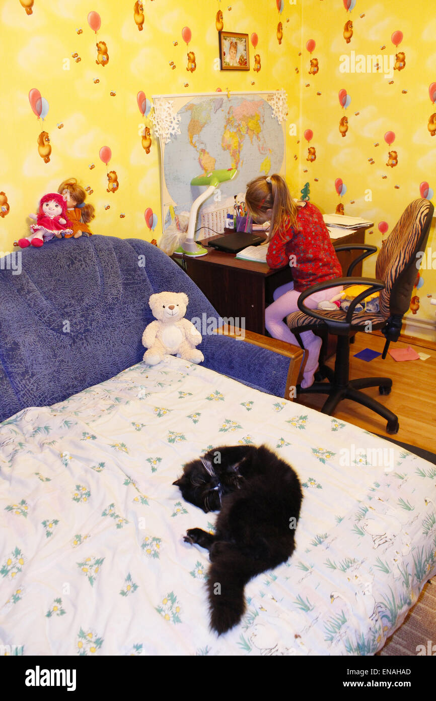 Gatto nero che giace prono sul letto nella stanza dei bambini Foto Stock