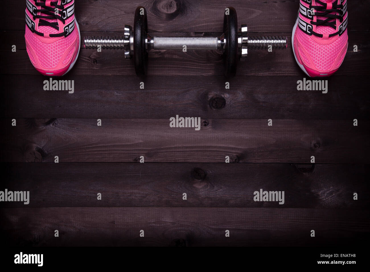 Attrezzature sportive. Sneakers e un manubrio su un nero lo sfondo di legno Foto Stock