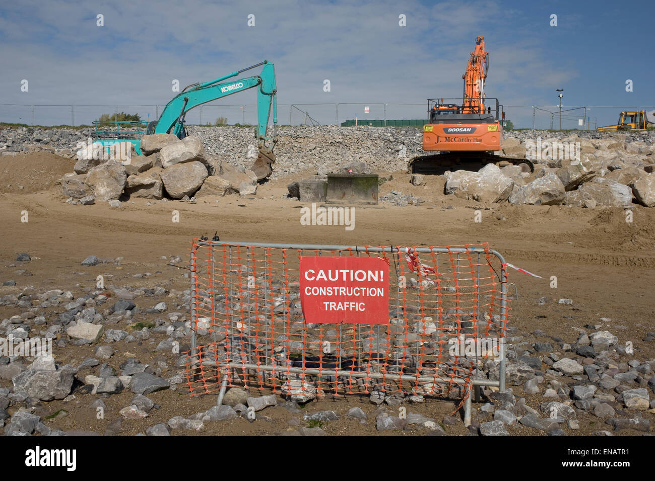 E Doosa escavatori Kobelco massi di sollevamento nel progetto per rafforzare la difesa del mare a Newton beach Porthcawl Foto Stock