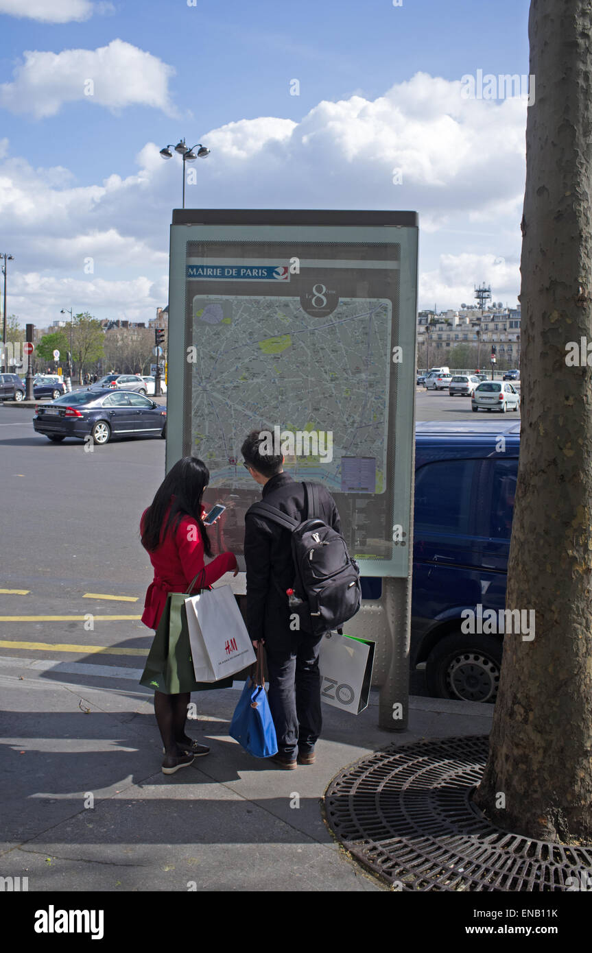 Due turisti giapponesi guardando una mappa a Parigi, Francia Foto Stock