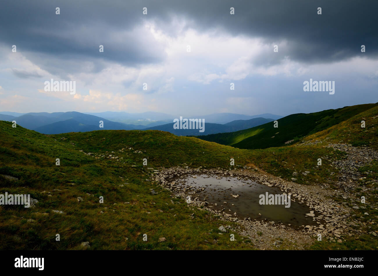 Pozza di fango in montagna con la vista su tutta la gamma Foto Stock