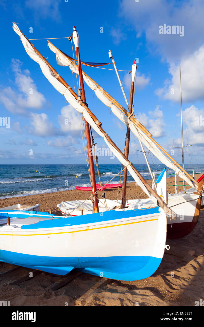 Di piccole dimensioni e di colore bianco e blu barche a vela poggiare sulla spiaggia di sabbia nella città di Calafell, Costa del mar Mediterraneo, la Catalogna, Spagna Foto Stock