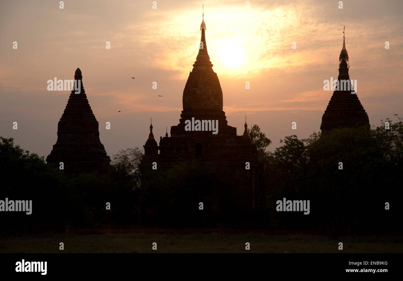 Tre sagome scure delle guglie del tempio contro il bagliore dorato di un tramonto Bagan Myanmar Foto Stock Tre sagome scure delle guglie del tempio contro il bagliore dorato di un tramonto Bagan Myanmar Foto Stock