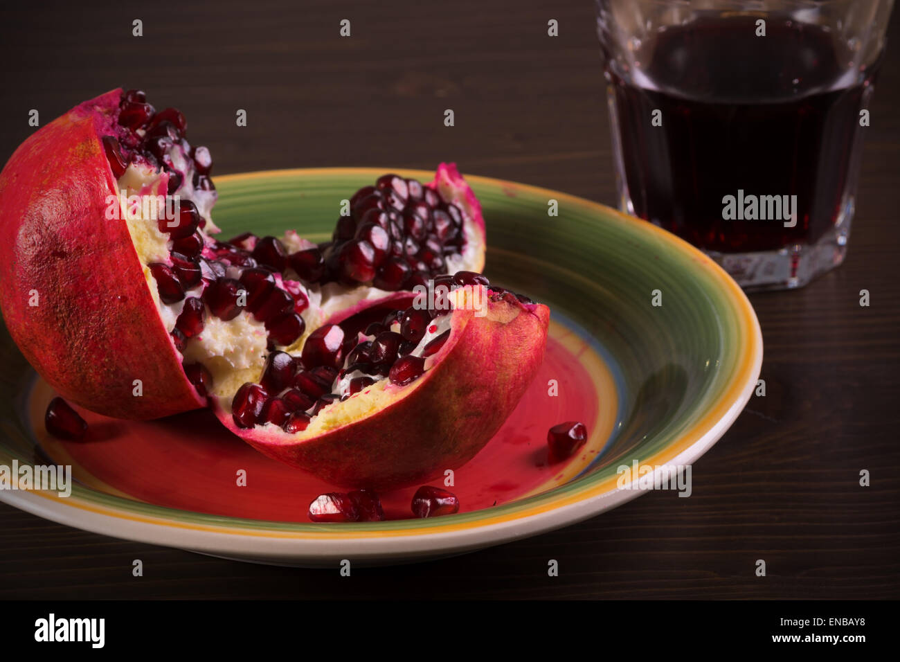Mature frutto di melograno e un bicchiere di succo di frutta su legno Foto Stock