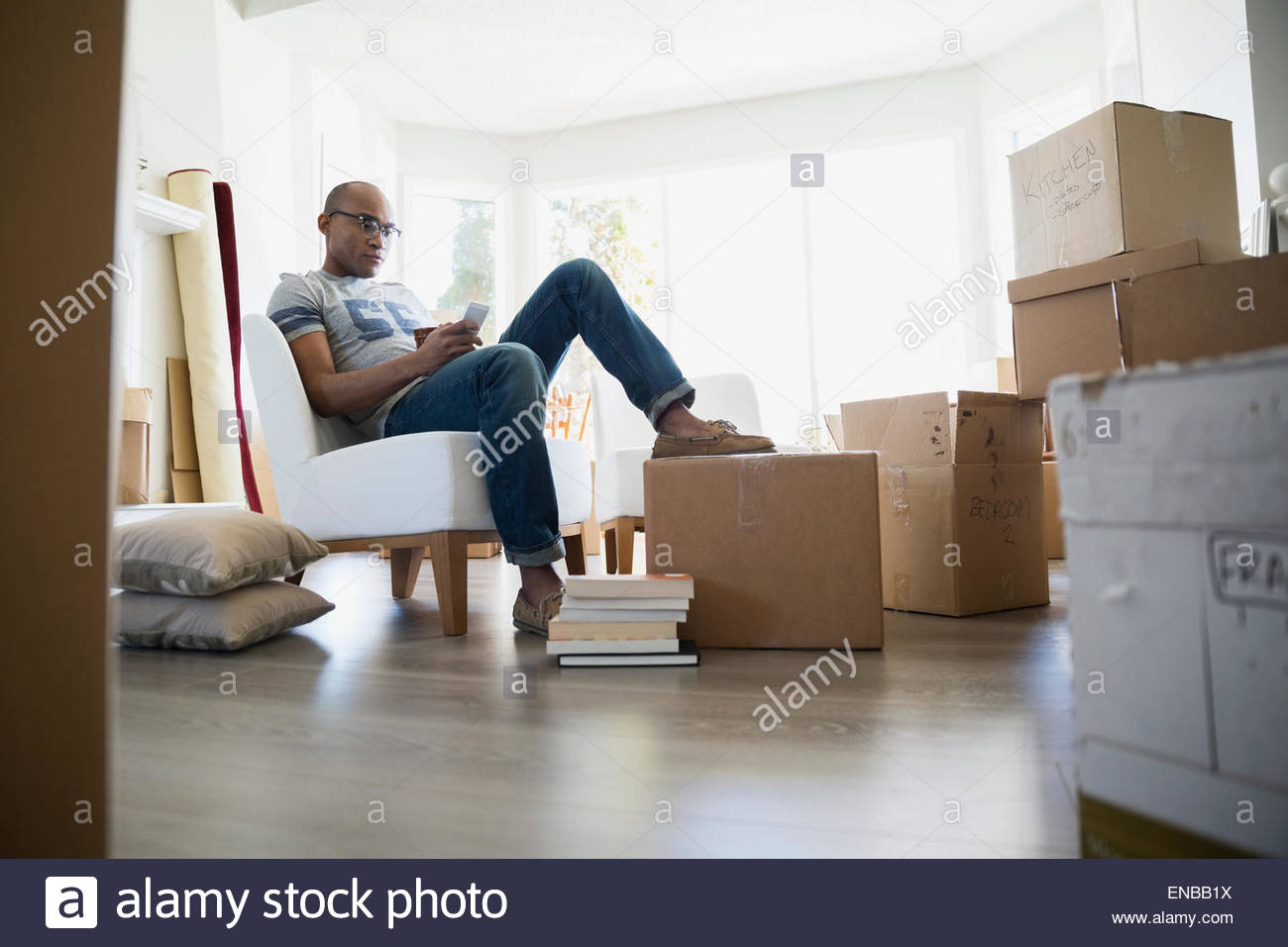 L'uomo texting circondato da contenitori per il trasloco Foto Stock