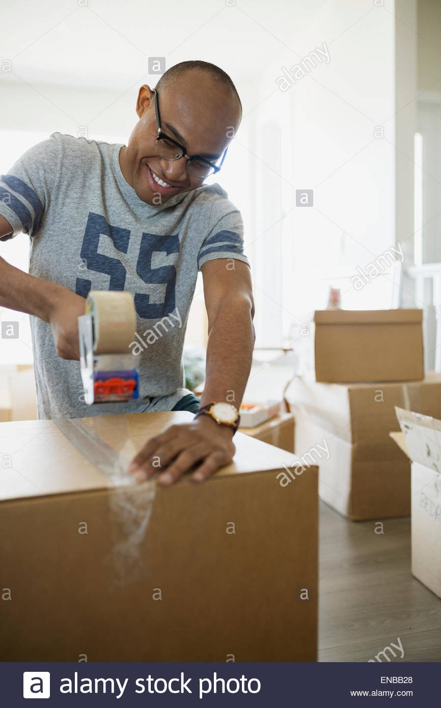 Uomo sorridente taping scatola di movimentazione Foto Stock