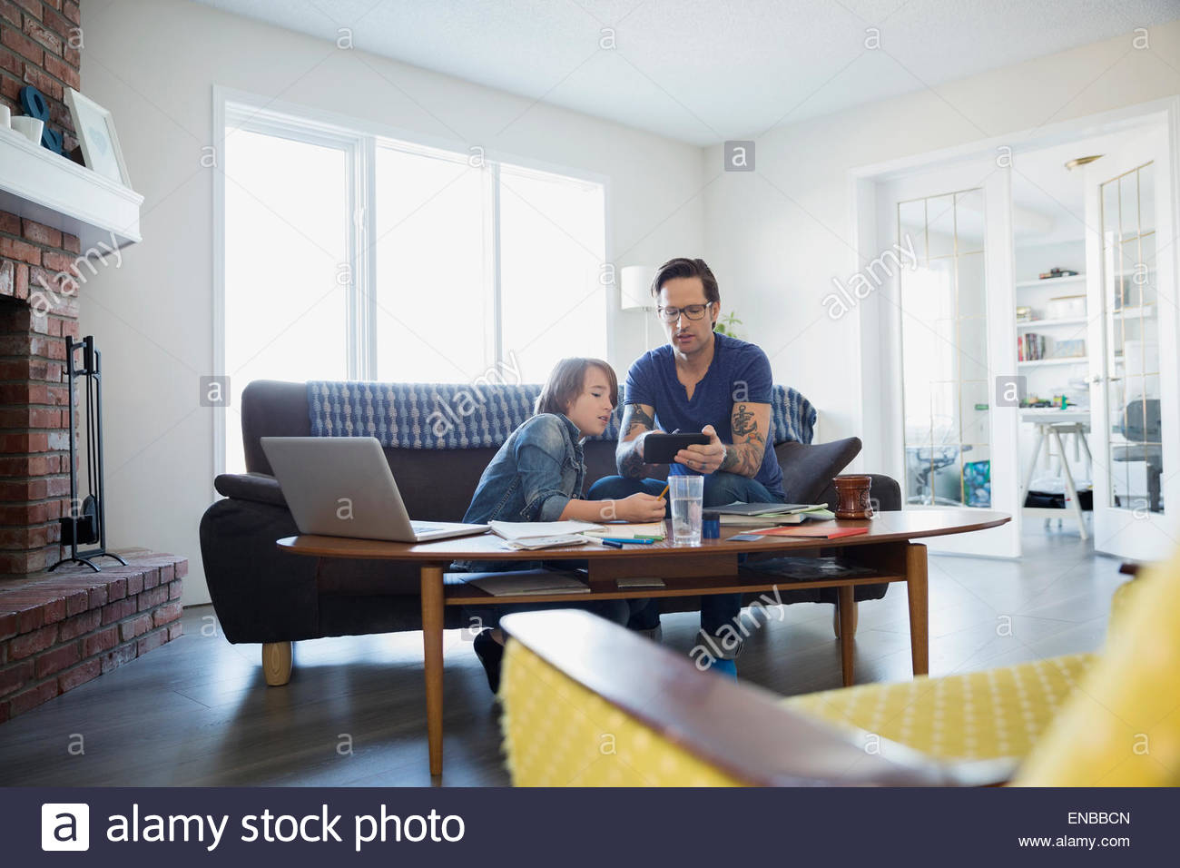 Padre aiutando figlio con i compiti in salotto Foto Stock
