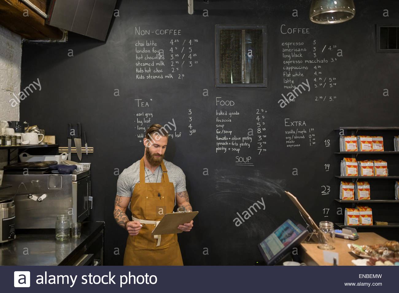 Hipster barista con appunti in coffee shop Foto Stock