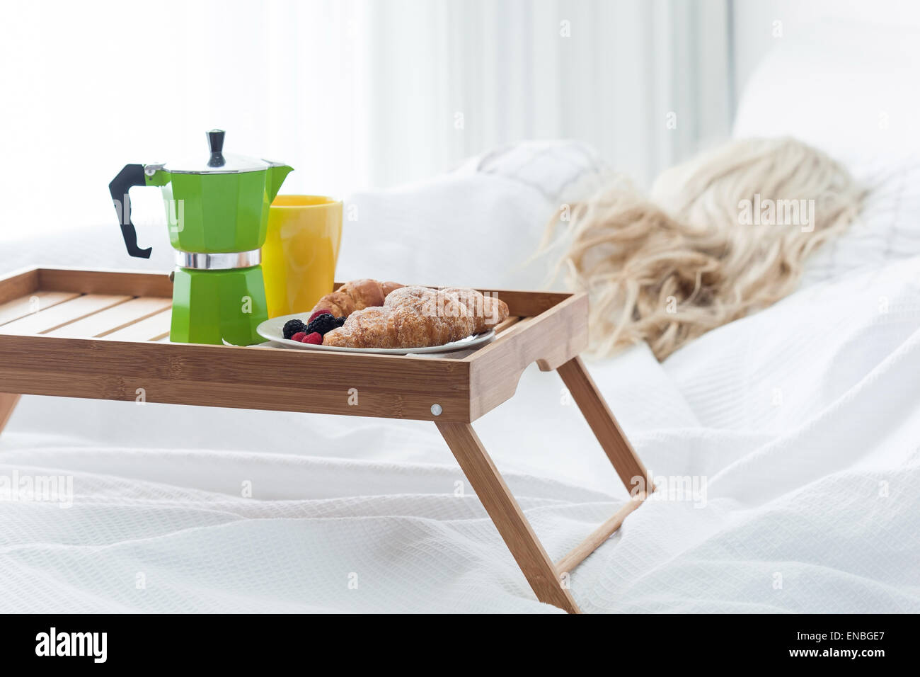 Colazione vassoio in legno con caffettiera e croissant sul letto, donna sfondo. Romantica sorpresa di mattina. Foto Stock