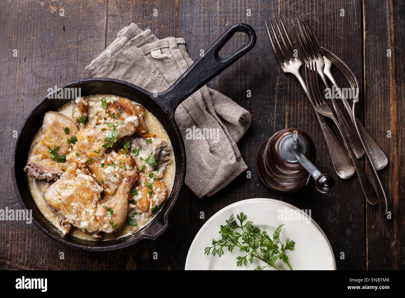 Pollo arrosto con cremosa salsa di aglio in ghisa padella scuro su sfondo di legno Foto Stock