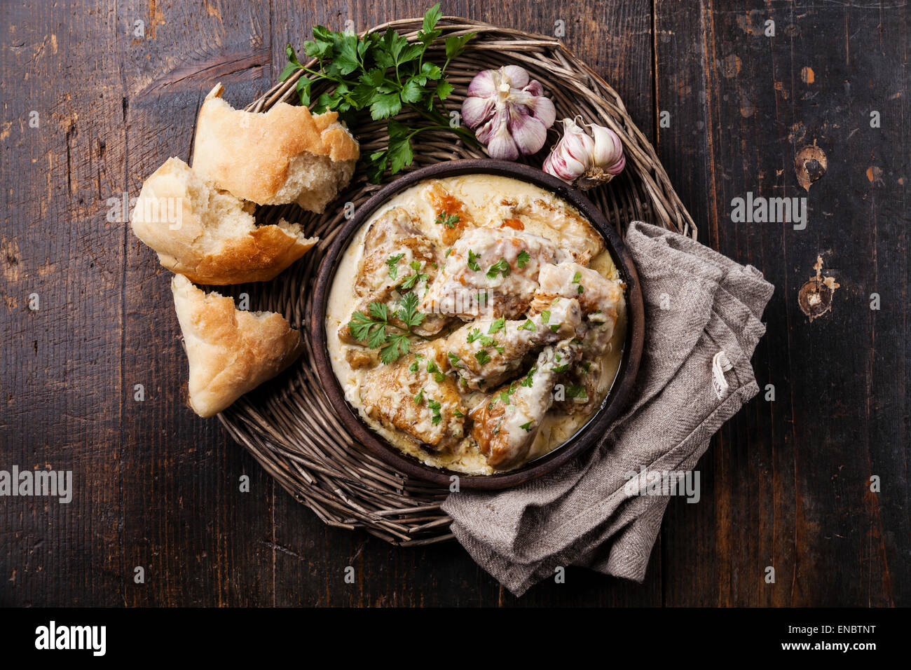 Pollo arrosto con cremosa salsa di aglio in argilla ketsi pan su scuro dello sfondo in legno Foto Stock