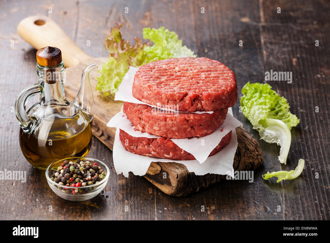 Materie di macinato di manzo hamburger di carne costolette di manzo e condimenti su scuro dello sfondo in legno Foto Stock