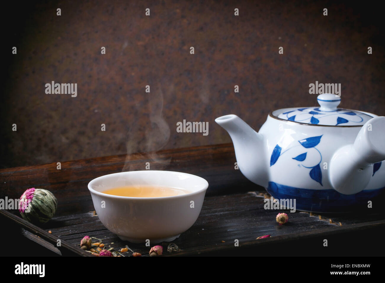 Giapponese tradizionale teiera e tazza di tè verde, servito sul bambù vassoio con tè secco variazioni su sfondo scuro Foto Stock
