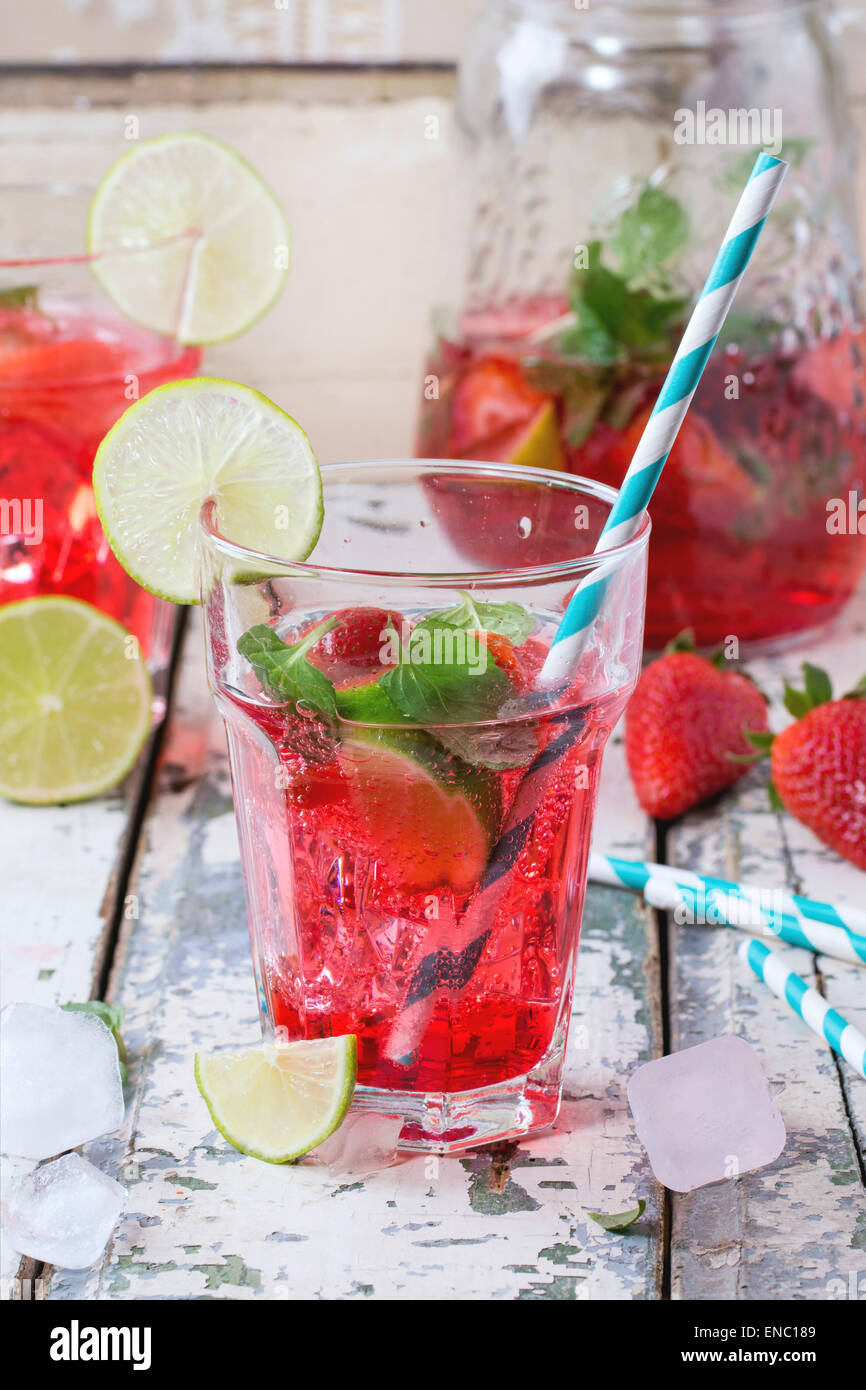 Due bicchieri con cocktail retrò tubi e caraffa di vetro di fragole fatta in casa la limonata, servita con fragole fresche, menta, calce Foto Stock