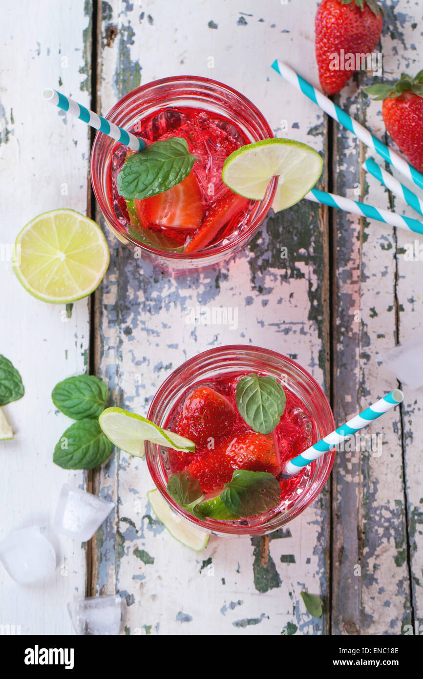 Due bicchieri con cocktail retrò tubi e caraffa di vetro di fragole fatta in casa la limonata, servita con fragole fresche, menta, calce Foto Stock