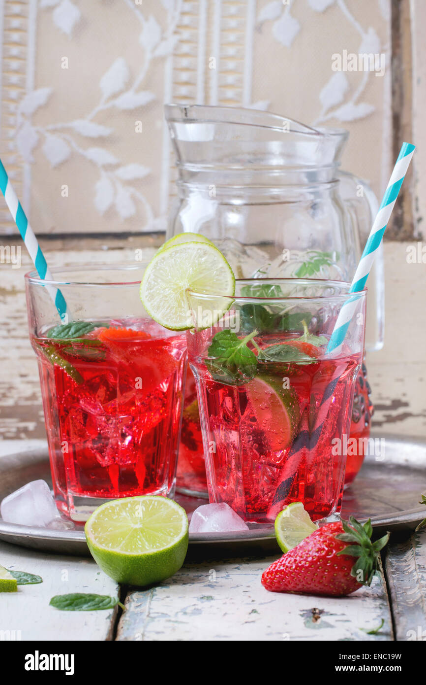 Due bicchieri con cocktail retrò tubi e caraffa di vetro di fragole fatta in casa la limonata, servita con fragole fresche, menta, calce Foto Stock