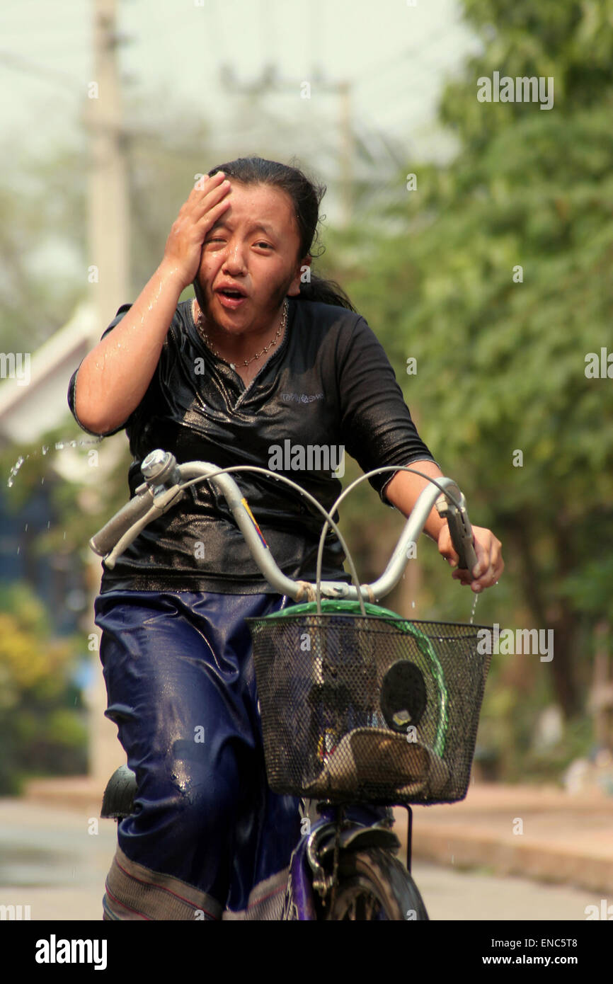 Una ragazza in sella ad una bicicletta reagisce ad essere colpita con acqua a Lao annuale Anno Nuovo (Pimai) Acqua Festival a Luang Prabang, Laos Foto Stock