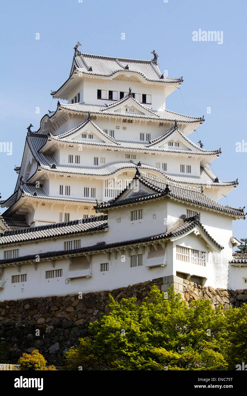 Il Ri-no-Ichi Watari Yagura, una torretta difensiva, con il torrione del castello di Himeji che torreggia contro un cielo azzurro primaverile. Luce solare intensa. Foto Stock