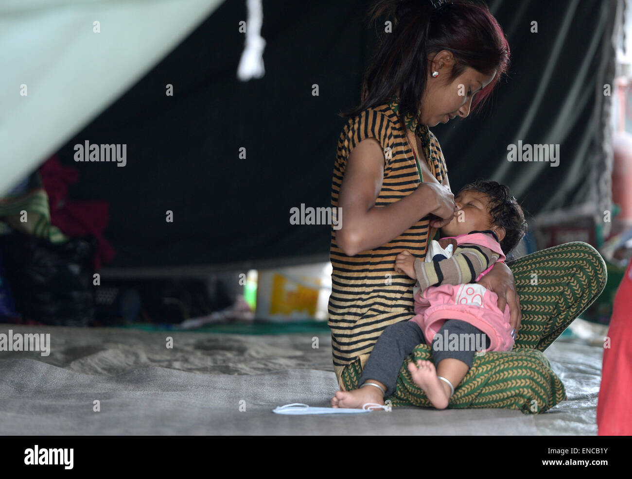 Kathmandu, Nepal. Il 2 maggio, 2015. Una donna che alimenta un bambino in Kathmandu, Nepal, il 2 maggio 2015. Il tributo di morte pagato lo scorso sabato potente terremoto in Nepal ha raggiunto 6,659 e un totale di 14,062 altri sono stati feriti, del paese home ministero ha detto il sabato. Credito: Qin Qing/Xinhua/Alamy Live News Foto Stock