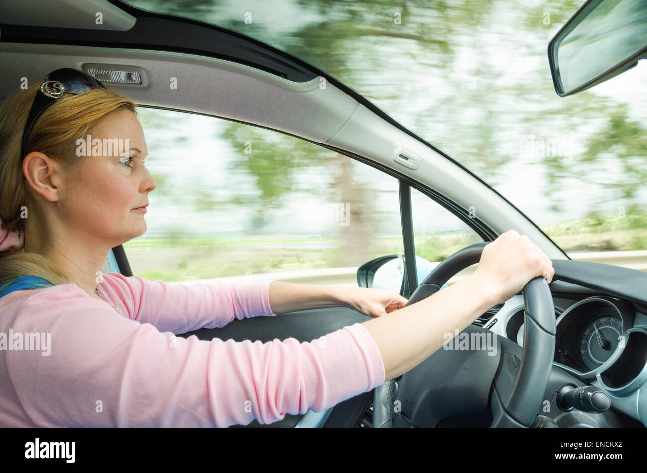 Ritratto di profilo di gravi calma donna attenta e guida sicura auto sulla strada di campagna. Foto Stock