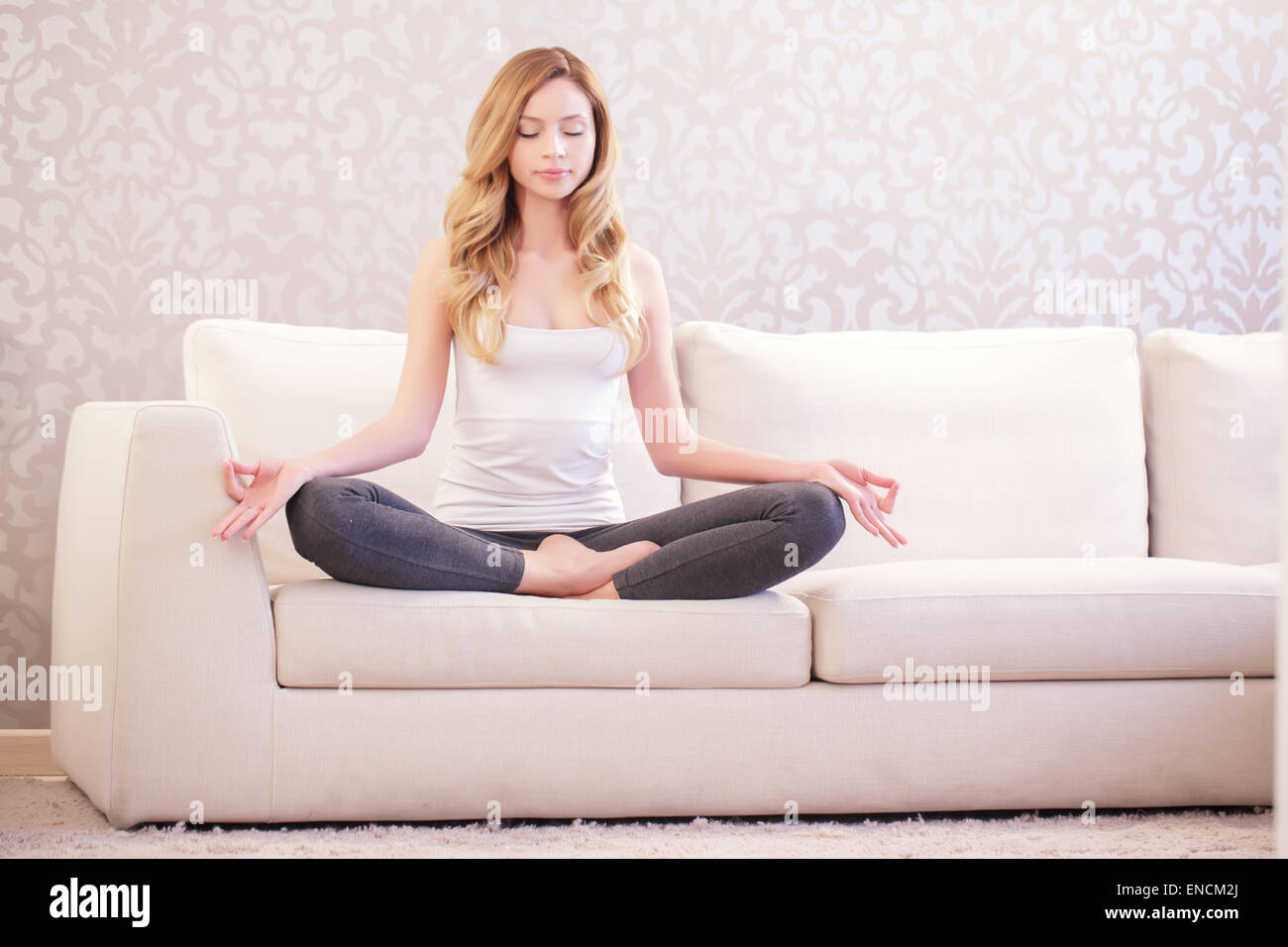 Bella Signora fare yoga sul divano Foto Stock