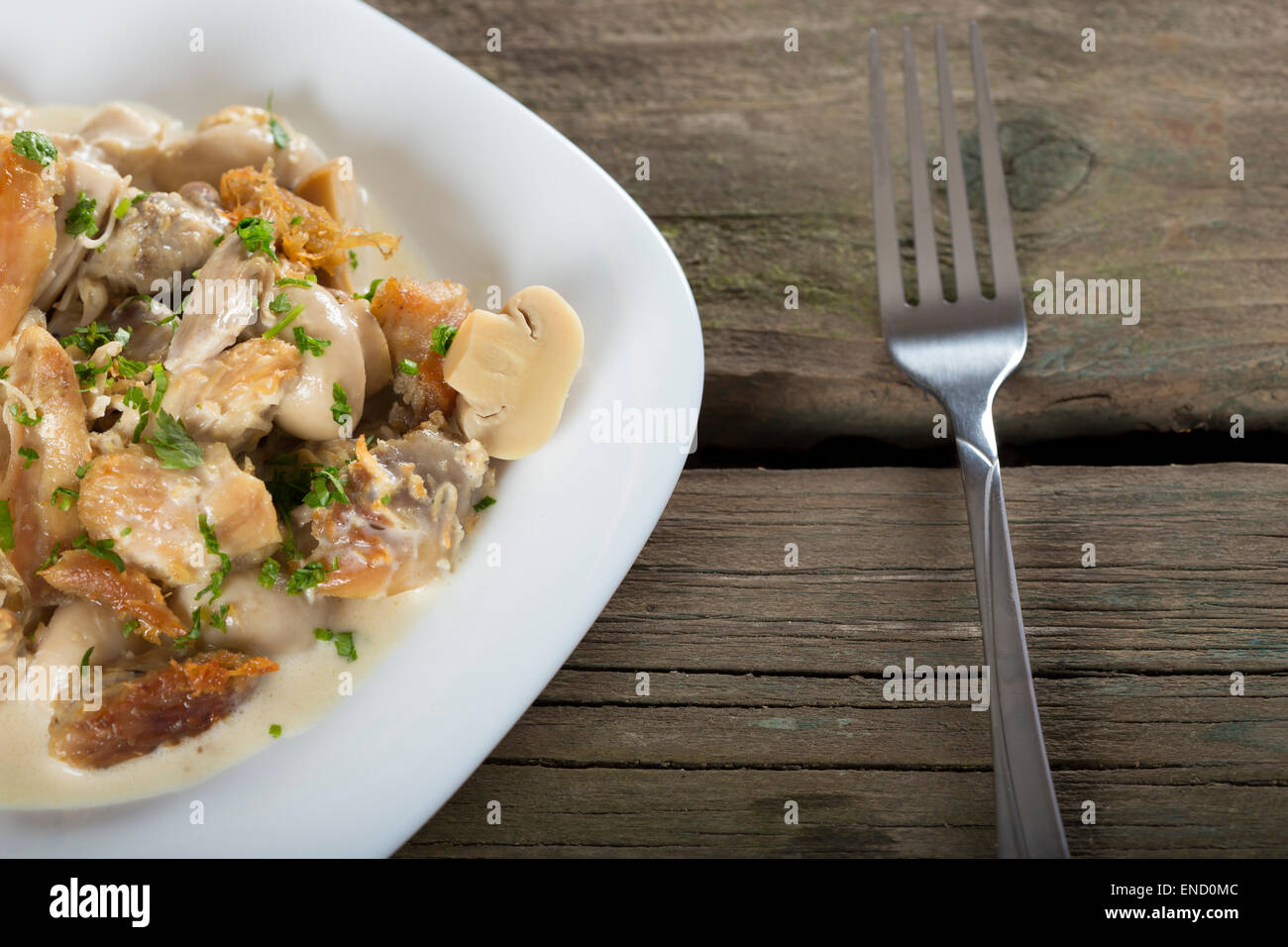 Lo stufato di pollo in una salsa cremosa con funghi su una piastra bianca con forca Foto Stock