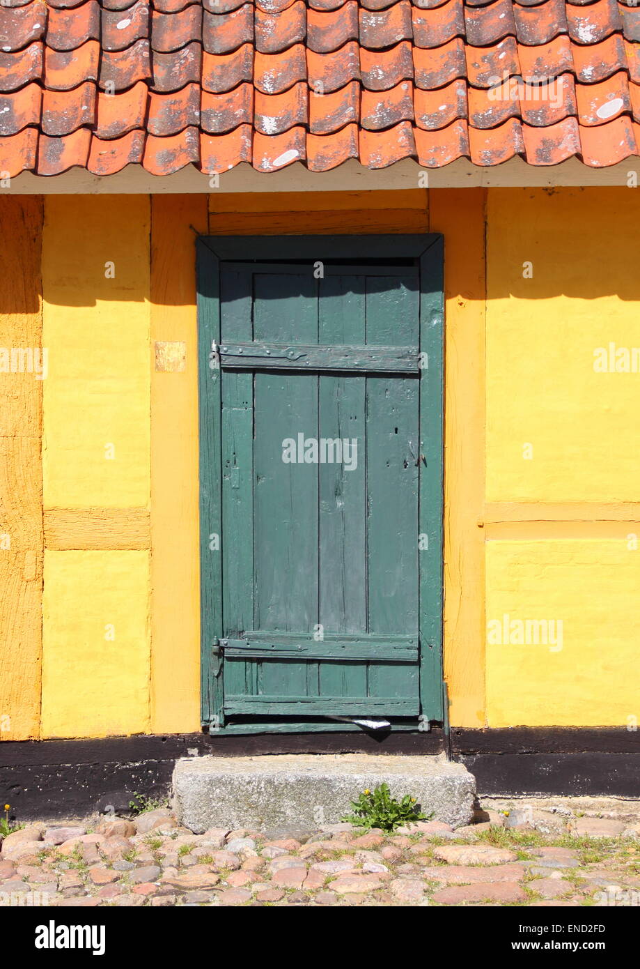 Vecchia porta di legno con tegole rosse e parete gialla Foto Stock