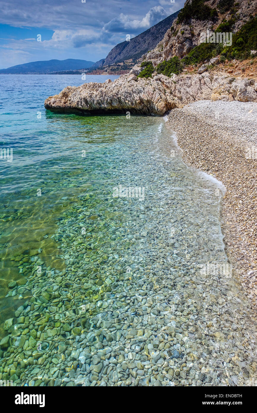Spiaggia ghiaiosa e poco profonde acque calme con rocce Foto Stock