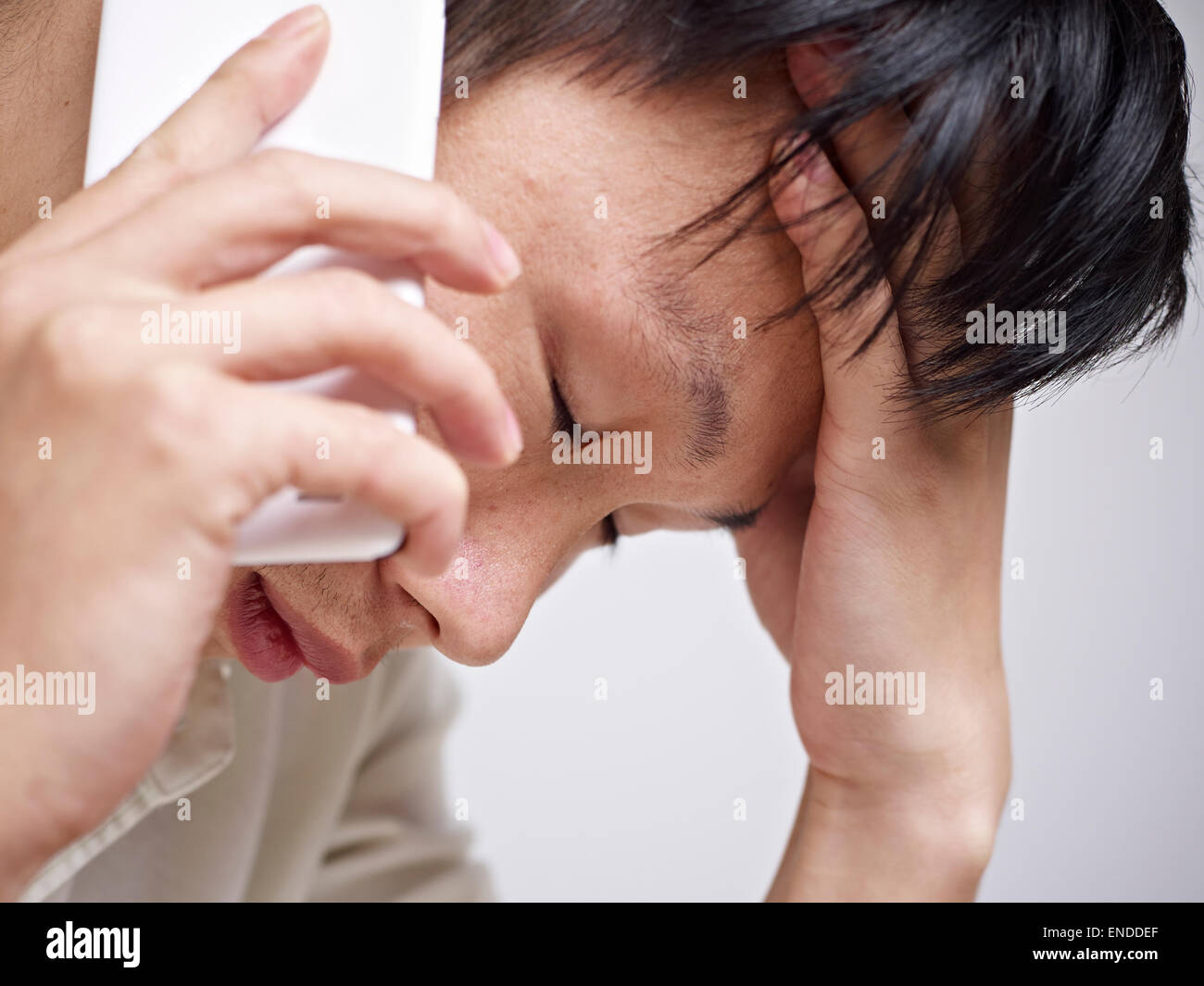 Giovane uomo cercando triste e depresso mentre parlano al telefono cellulare Foto Stock