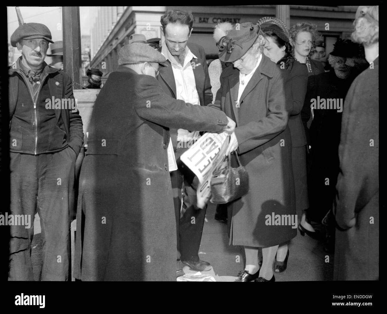 Questa fotografia cattura il momento in cui una persona acquista un giornale V-e Day, che commemora la fine della seconda guerra mondiale in Europa. L'immagine riflette il significato storico del giorno e la risposta del pubblico alla notizia della vittoria. Foto Stock