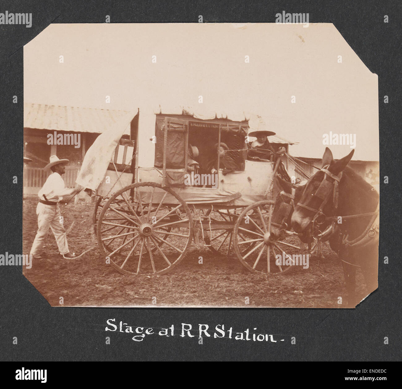 Una scena storica in una stazione ferroviaria con una diligenza e asini, che illustrano i primi metodi di trasporto nei depositi ferroviari. L'immagine cattura la transizione tra i viaggi ferroviari e su strada nel XIX secolo. Foto Stock