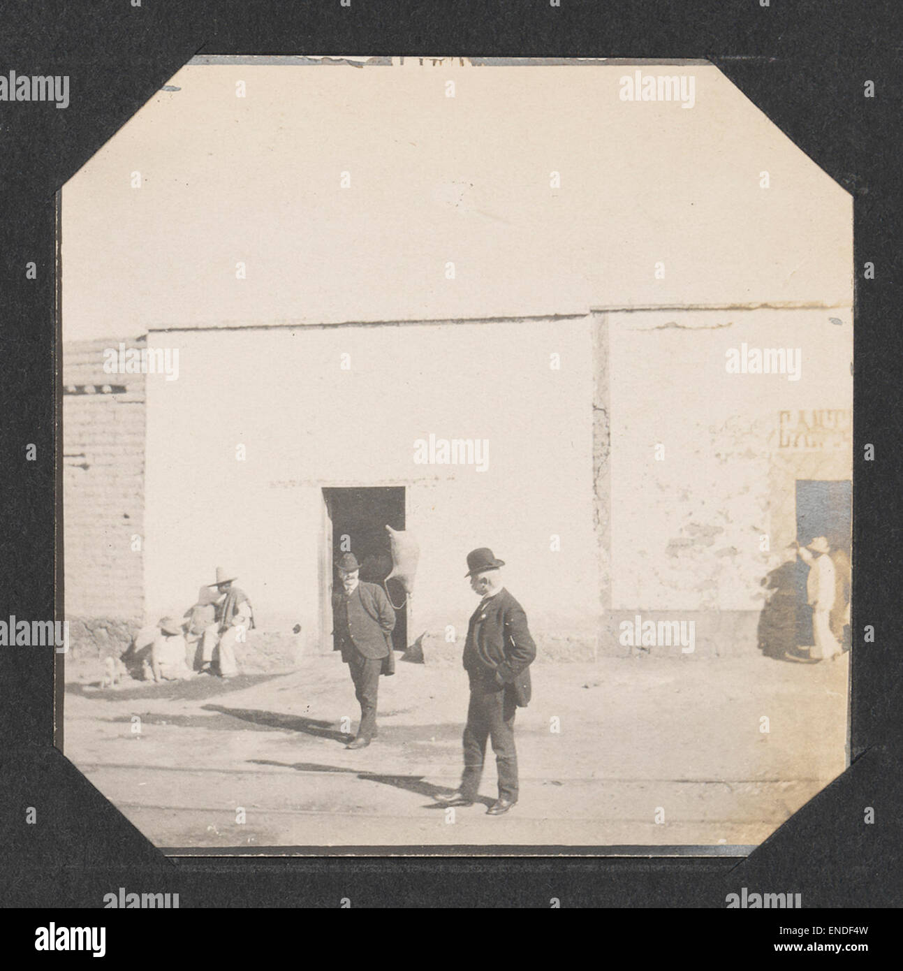 Un'immagine storica che mostra due uomini in una strada, con locomotive, cavalli e treni sullo sfondo. La scena riflette la fusione di metodi di trasporto tradizionali e moderni durante il periodo. Foto Stock