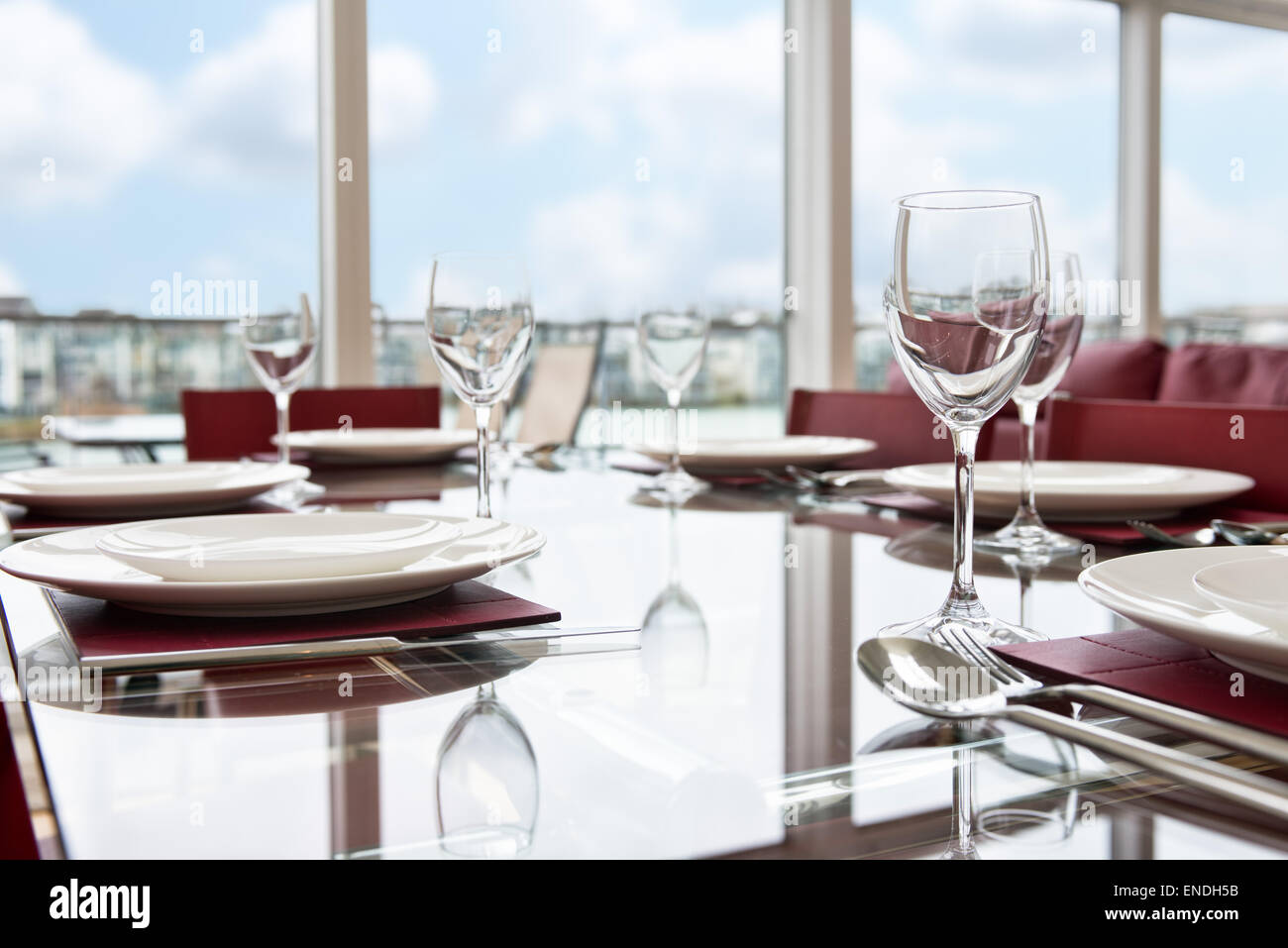 Un vetro tavolo da pranzo insieme con le regolazioni del posto, bicchieri da vino & Piastre per un pasto di festa Foto Stock