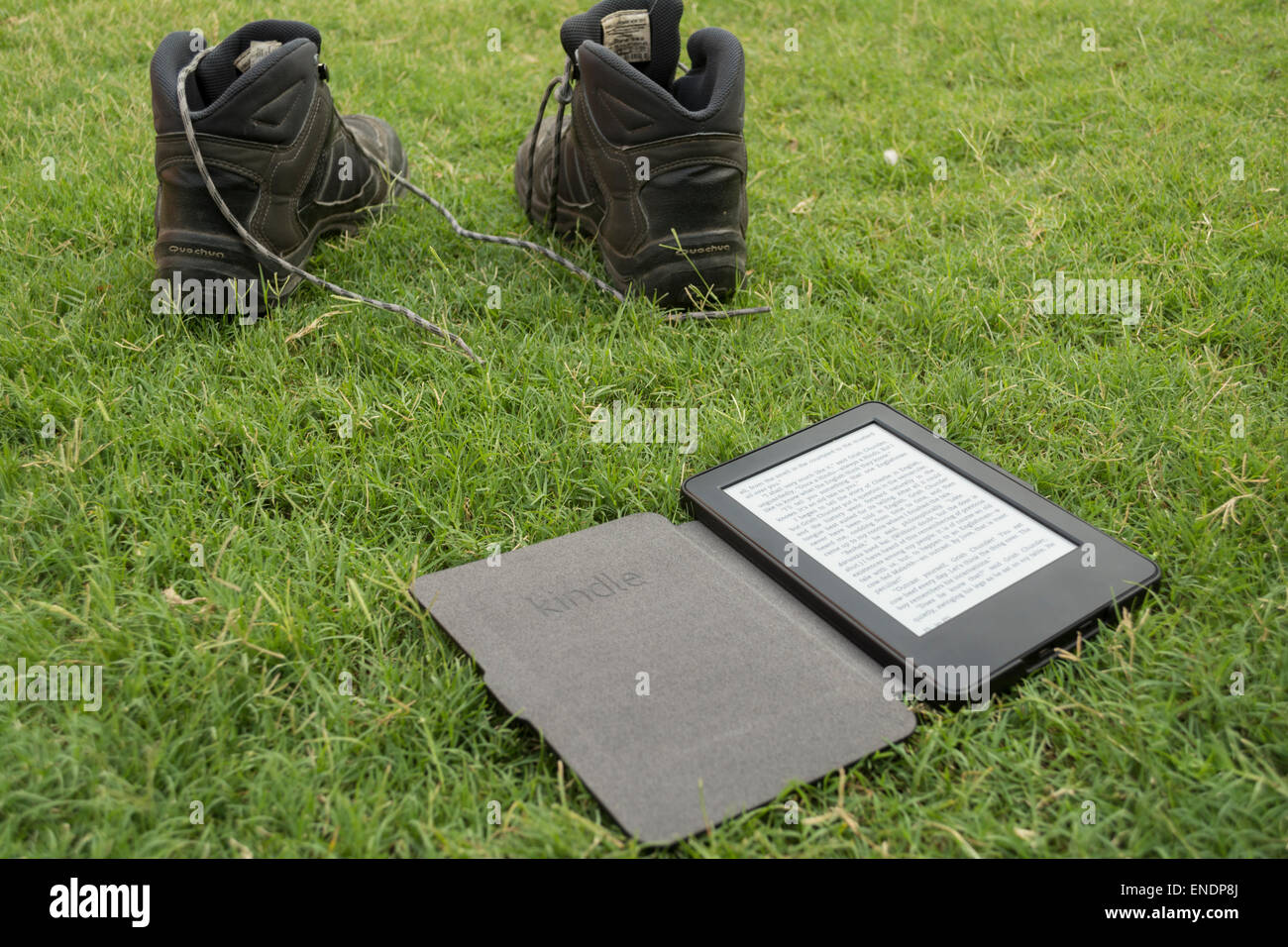 Amazon Kindle Reader di e-book su erba con calzatura trekking nelle vicinanze Foto Stock