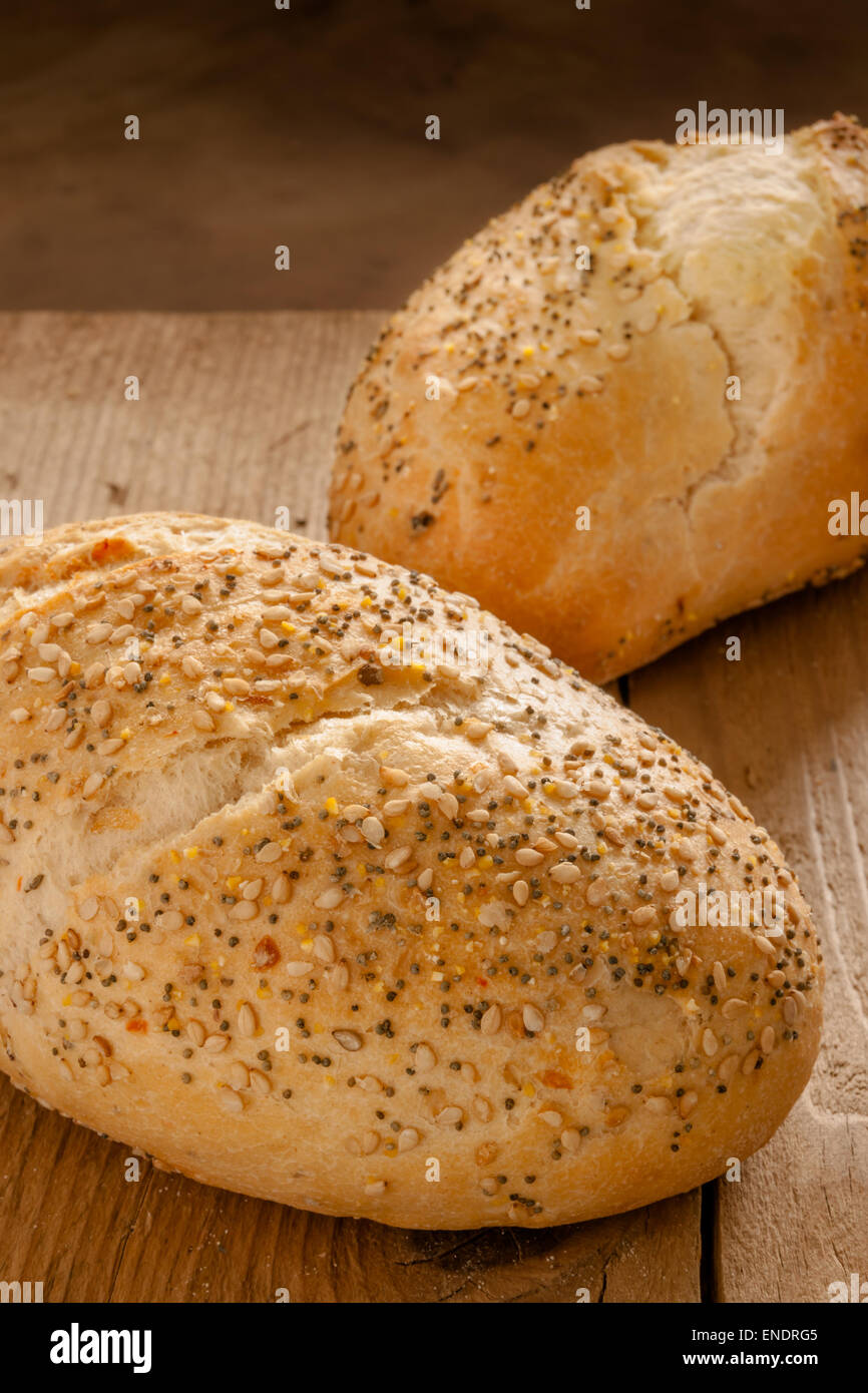Rustico baguette seminate piccole pane appena sfornato rotoli incrostato con semi di papavero e semi di sesamo Foto Stock