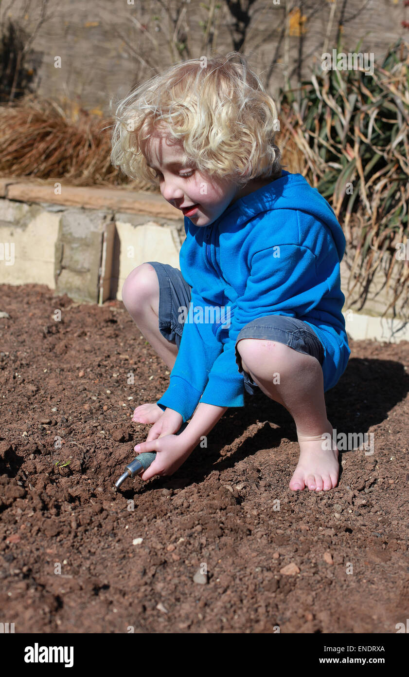 Poco dai capelli biondi boy giardinaggio in una giornata di sole Foto Stock