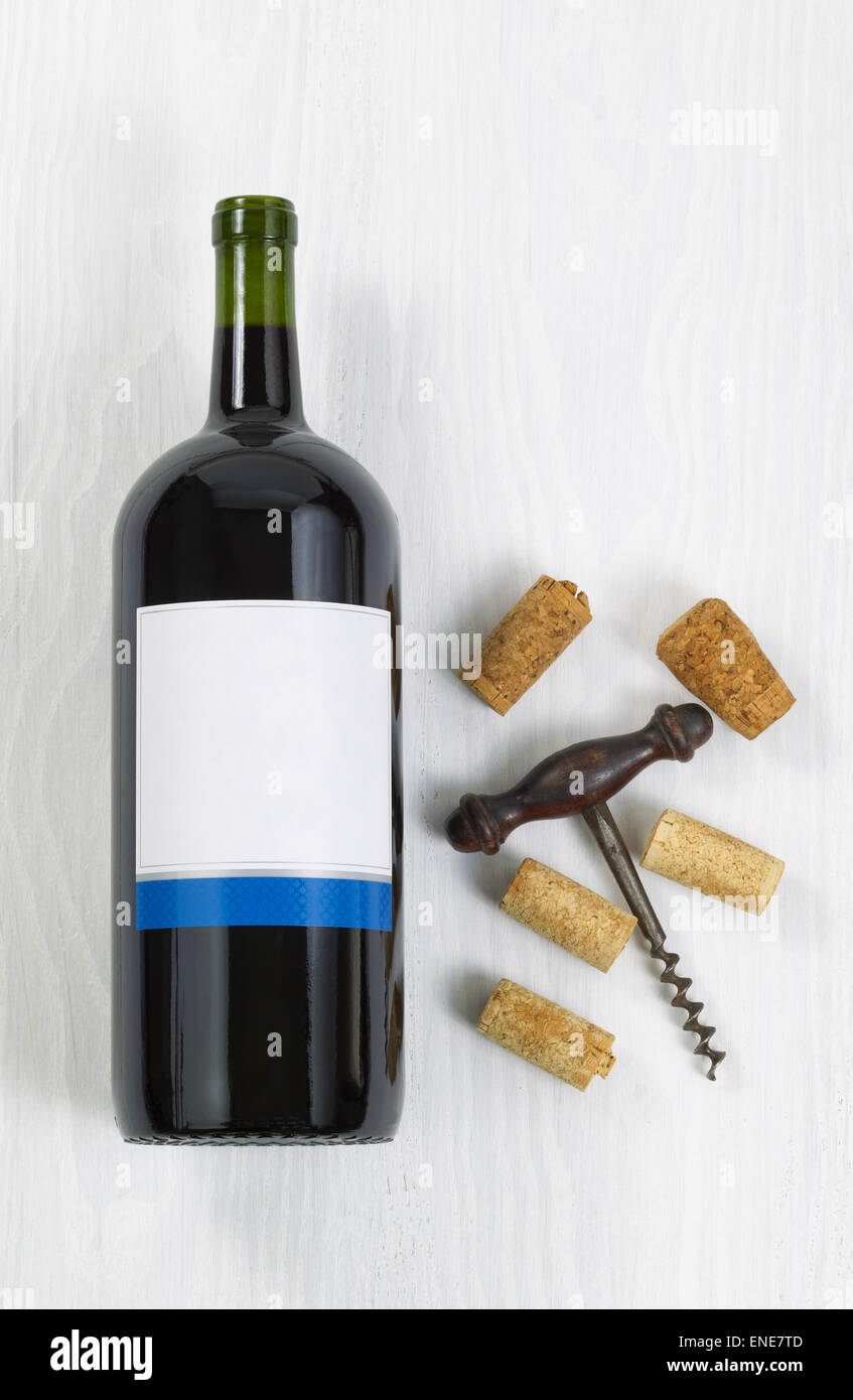 L'immagine verticale una bottiglia grande di vino rosso con un antico cavatappi con vecchi tappi in legno bianco. Foto Stock