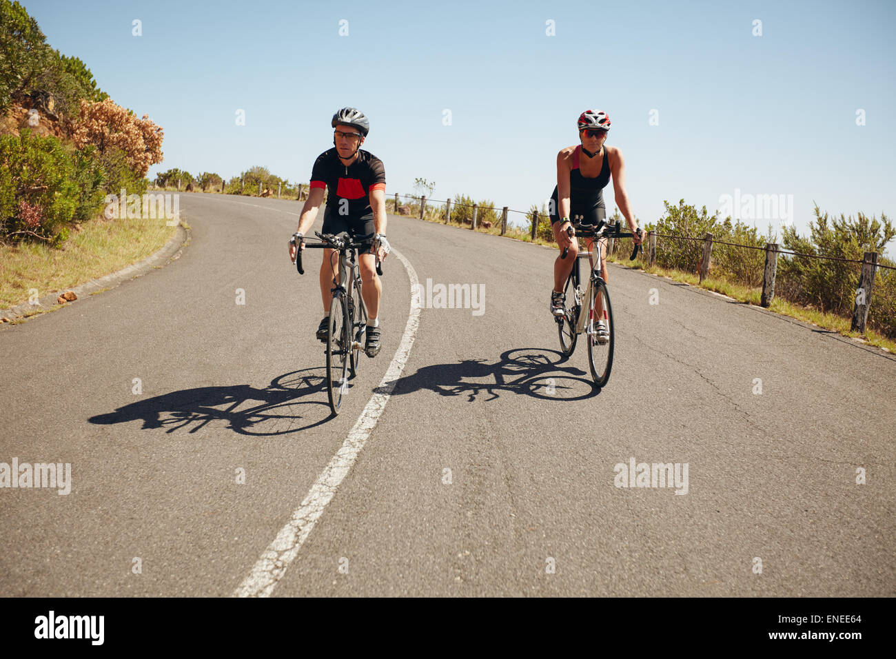 I ciclisti in sella verso il basso di una panoramica strada di campagna. Triatleti racing su una bicicletta su una strada di campagna Foto Stock