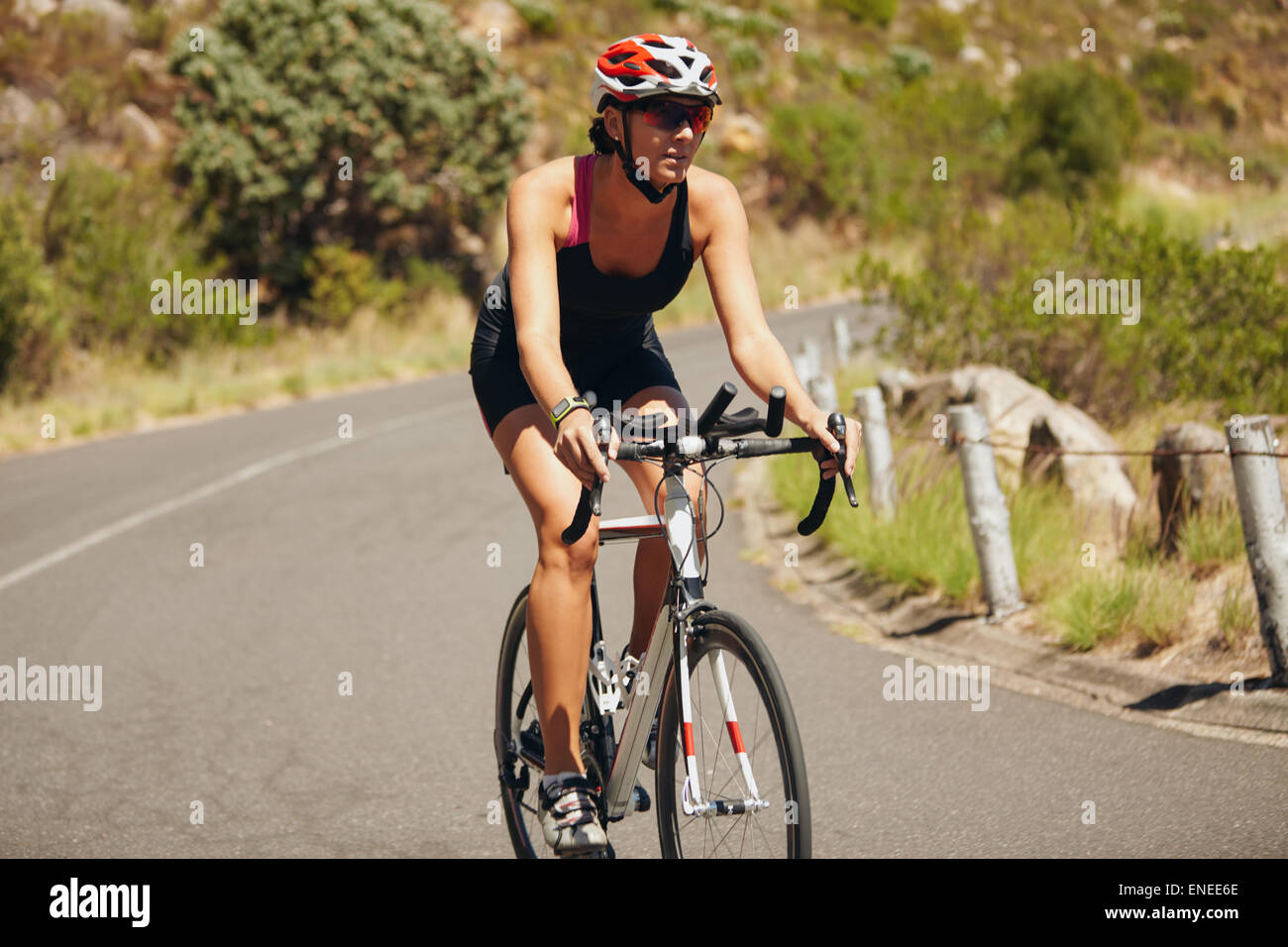 Donna giovane atleta triathlon cycling. Caucasian atleta femminile ciclo di equitazione sulla strada di campagna. Foto Stock