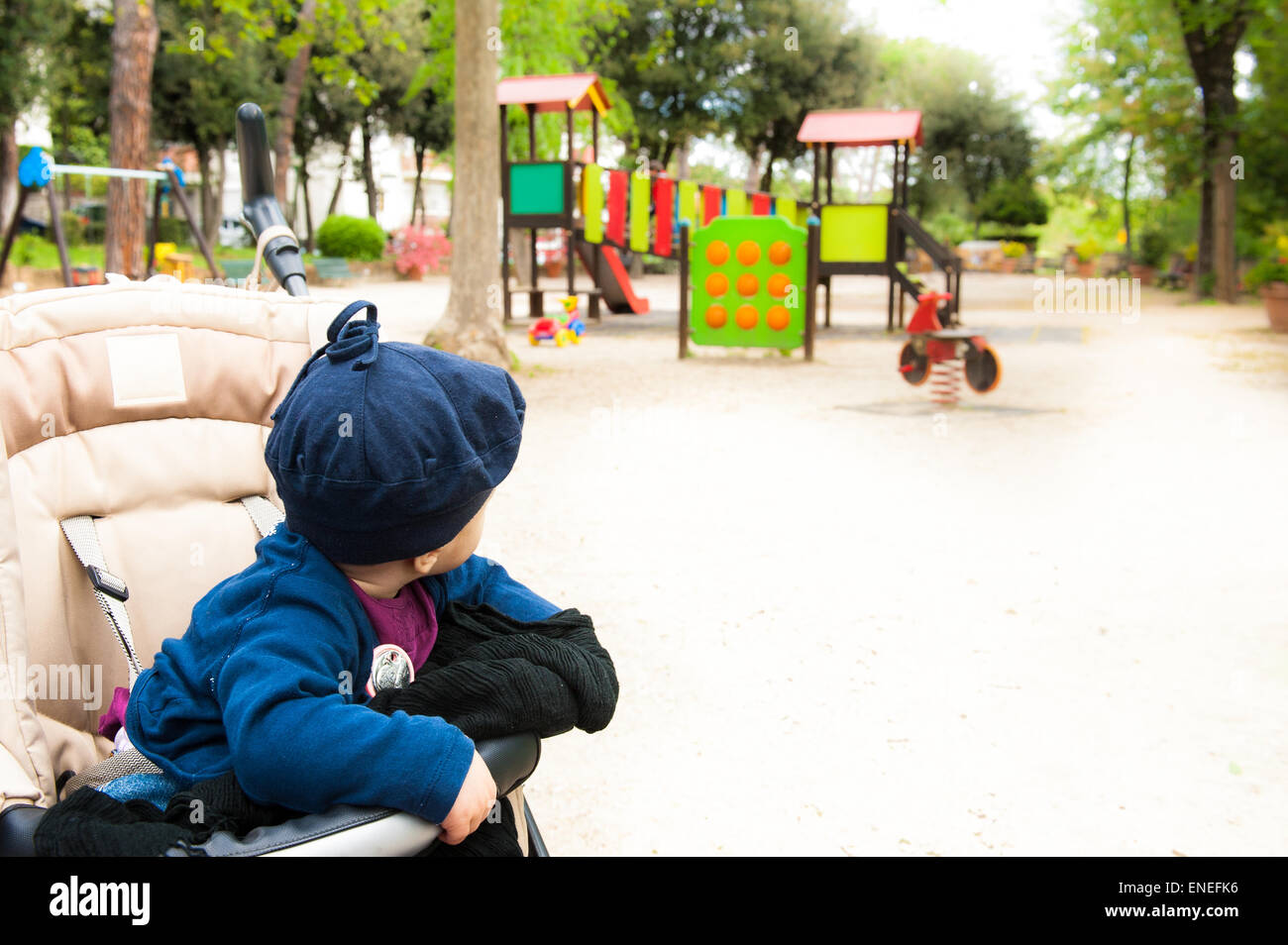 Piccolo bambino sul passeggino guardando i giochi colorati per senior neonati nel giardino della città Foto Stock